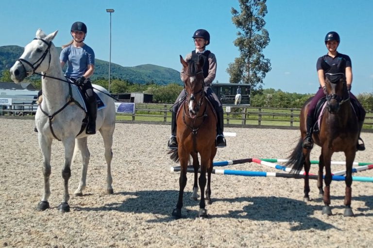 three riders enjoying a horse riding lesson on horses in a on horses in a worcestershire arena. kat williams-jones polework clinic in worcestershire